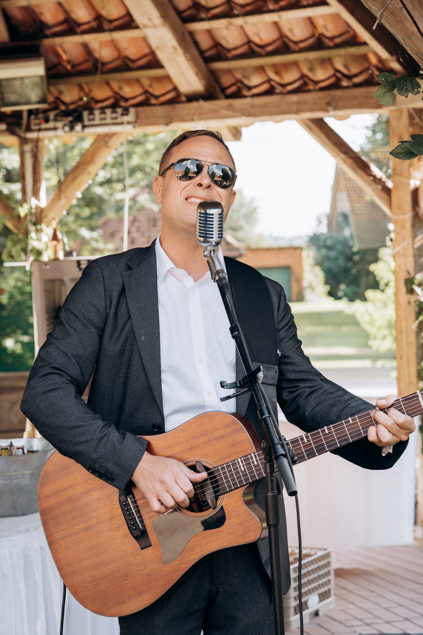 John Eid spielt Gitarre und singt bei einer Hochzeit unter einem Pavillon